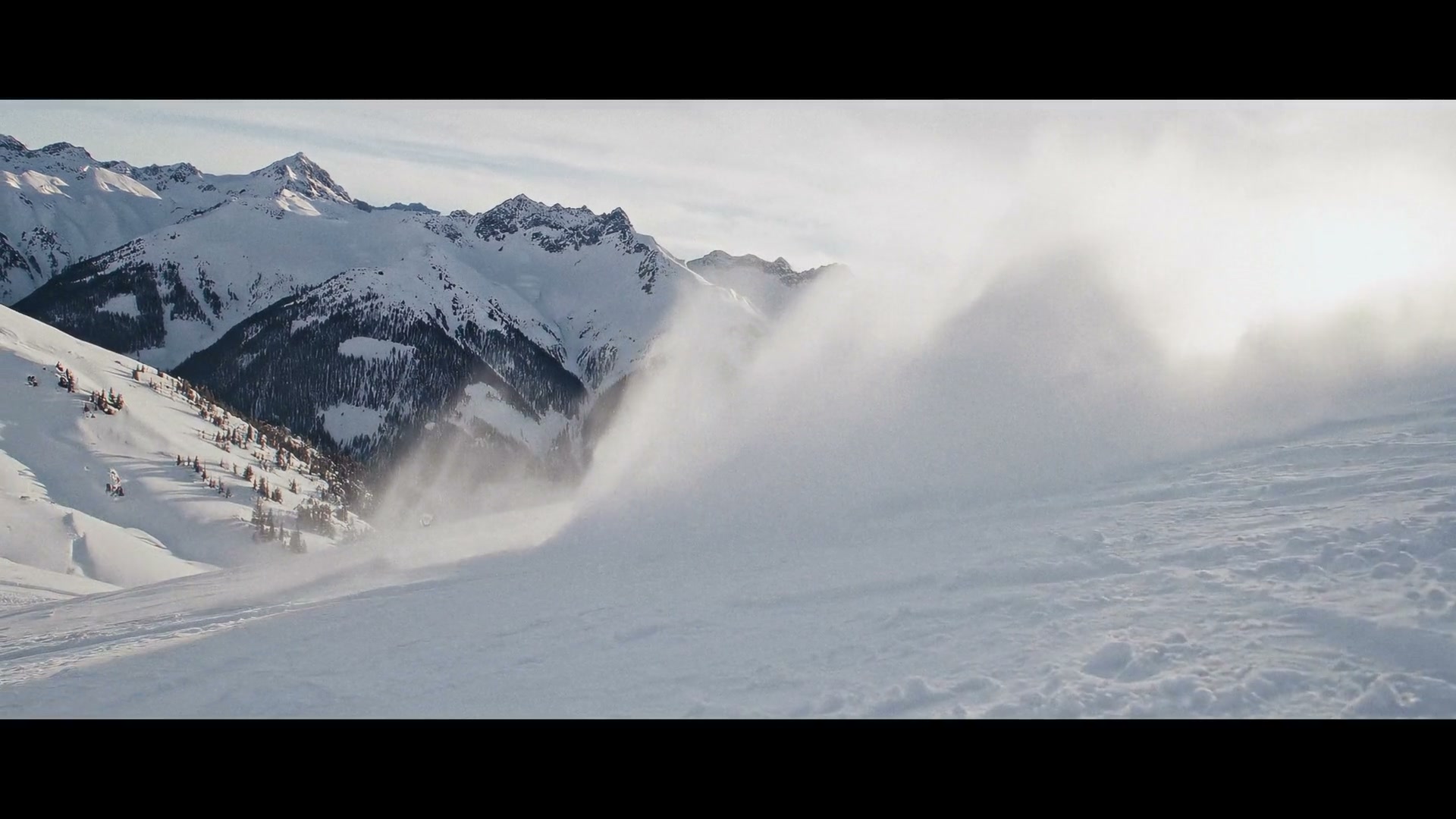 Skier disappearing into a cloud of powder against a mountain range in Adrenaline Junkies