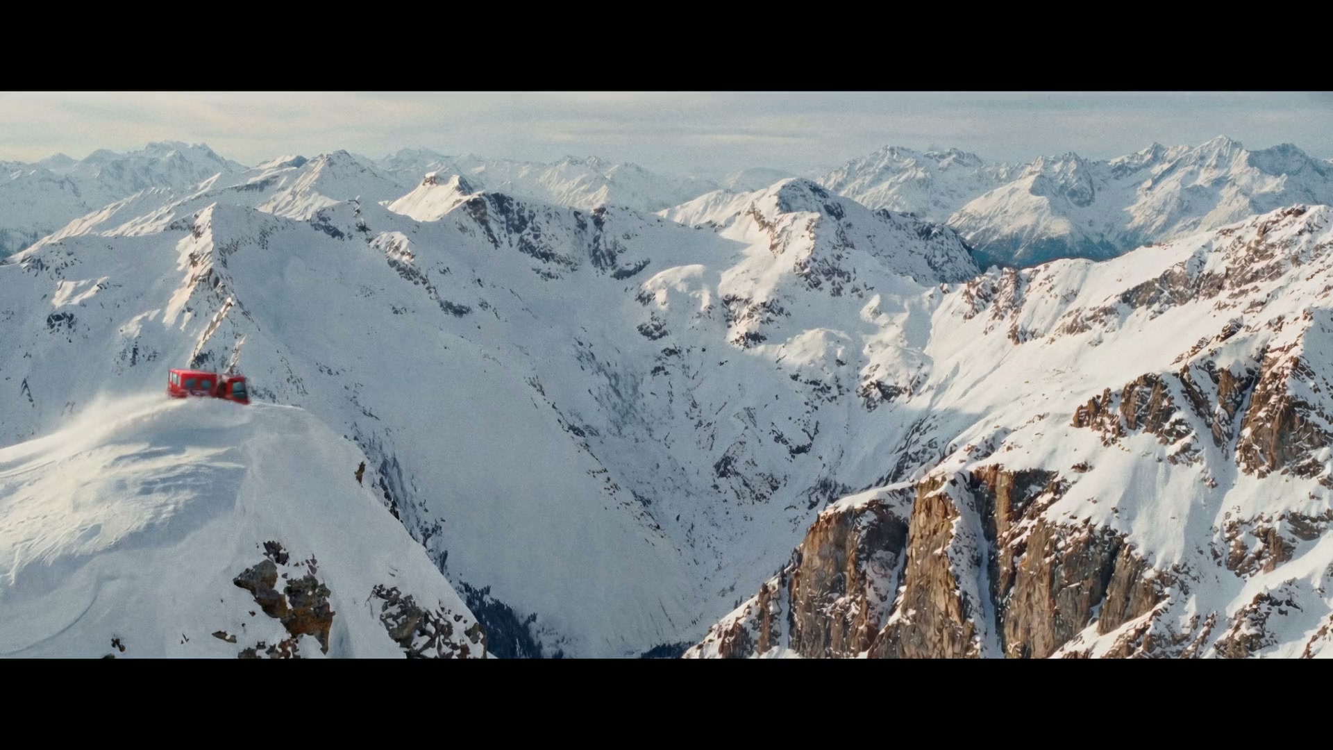 Red snowcat driving along a narrow snowy mountain ridge in Adrenaline Junkies