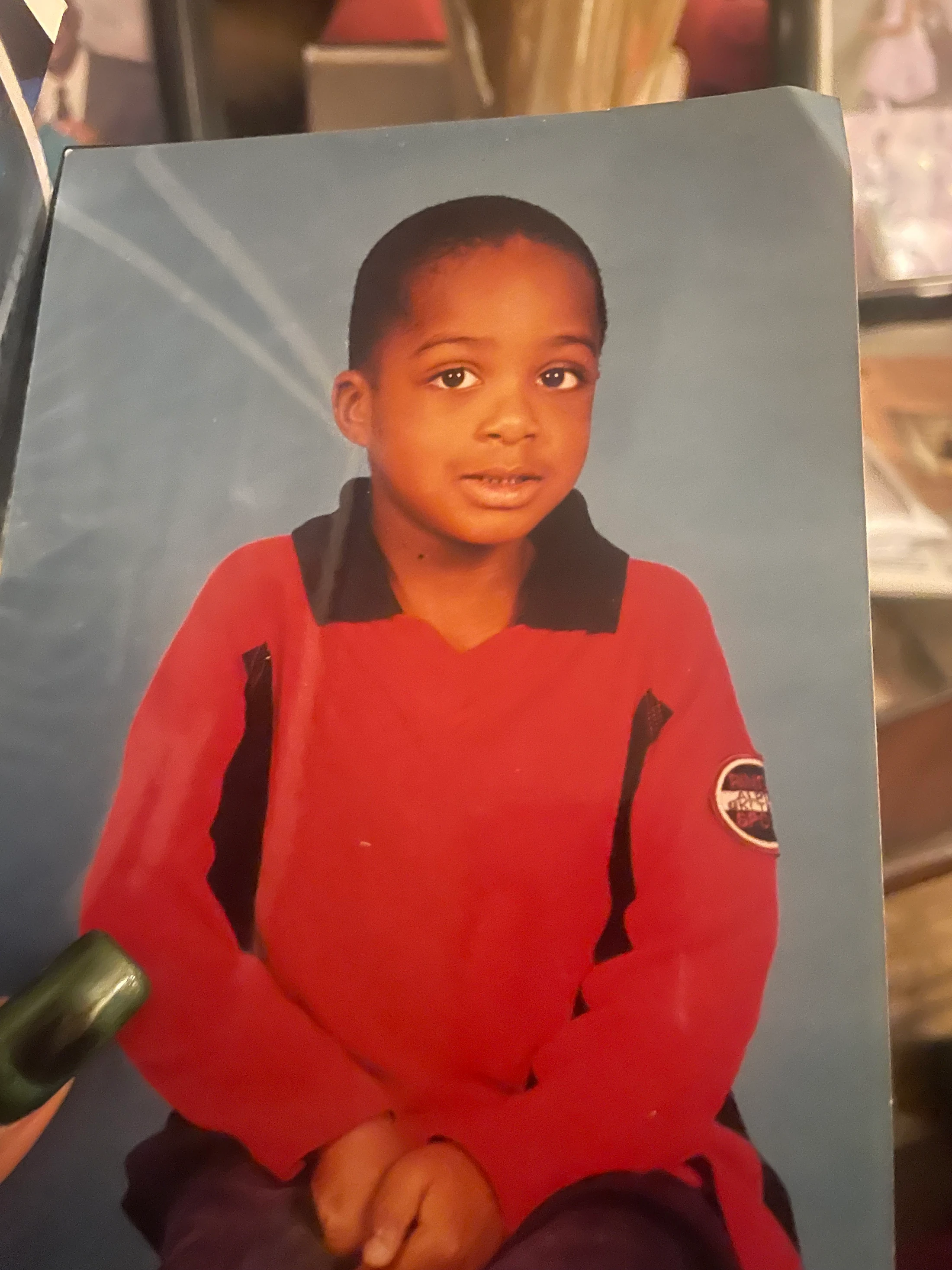 Original printed studio portrait of a child in a red shirt against a blue background