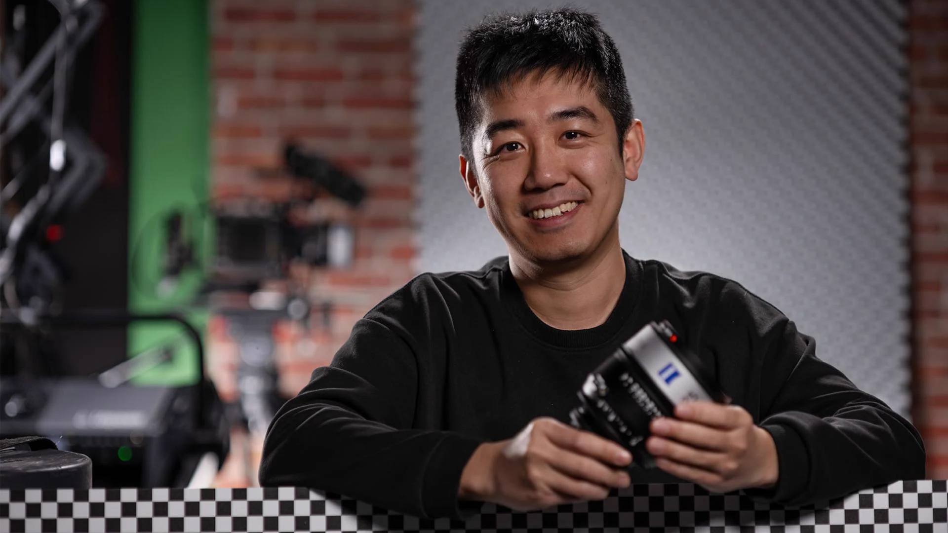 ZEISS optical designer Xiang Lu holding an Aatma cinema lens beside a camera