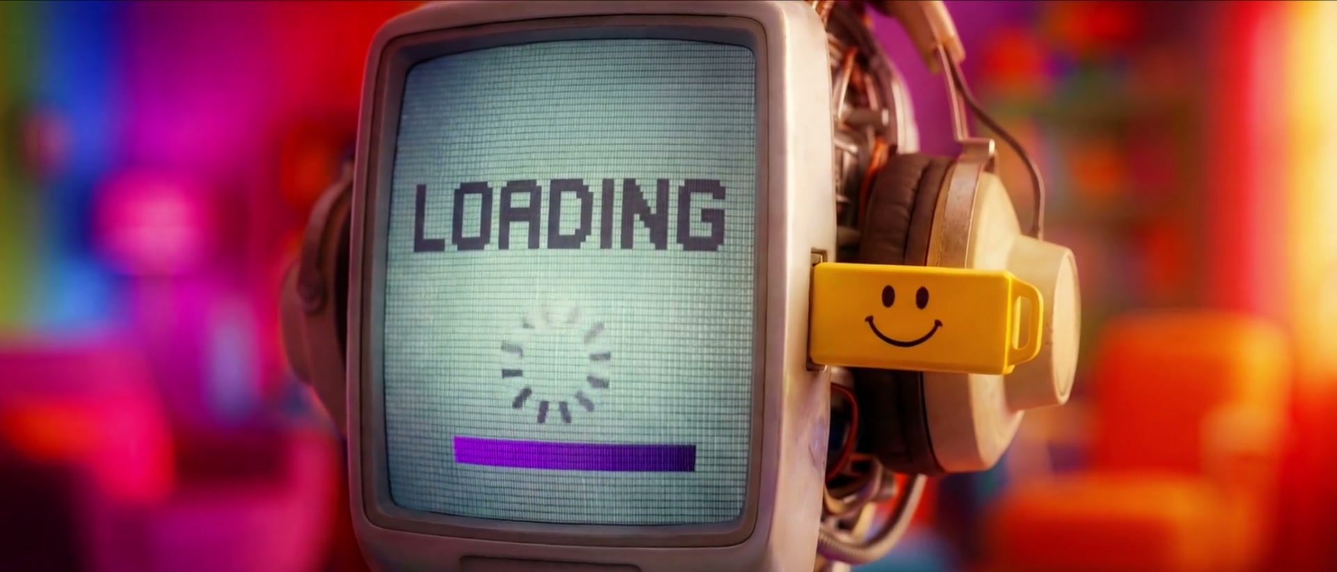Screen-faced robot character seated beside a human colleague in an office scene