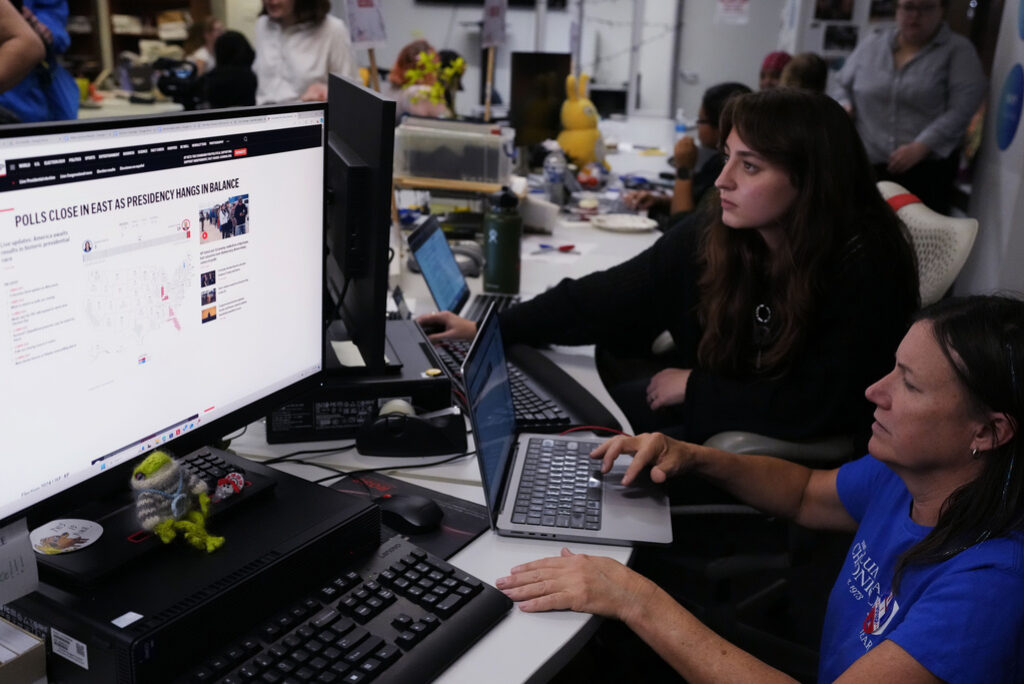 An adviser and student reviewing an election story together in a newsroom