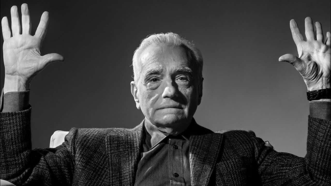 Black and white image of Martin Scorsese with both hands raised
