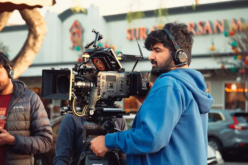 Camera operator working beside a cinema camera on a film set