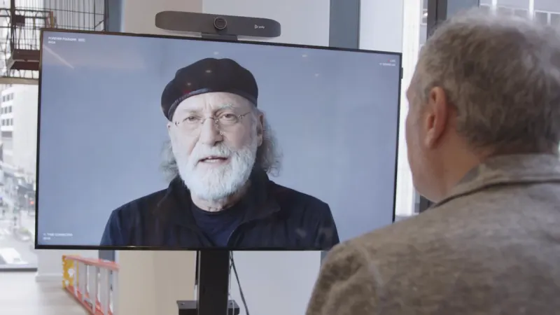 A guest speaking to R/GA founder Bob Greenberg's live AI avatar on a large screen