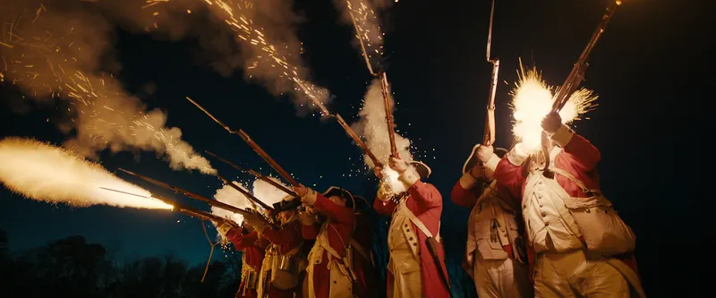 Battle reenactment from Netflix documentary The American Experiment with period soldiers firing muskets at night