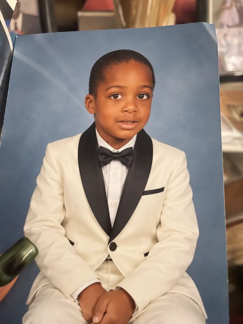 Edited studio portrait of a child in an ivory tuxedo against a blue background